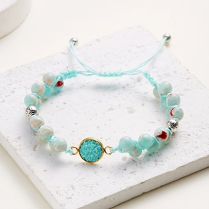 Primer plano de pulsera trenzada hecha a mano con cuentas azul claro y colgante dorado