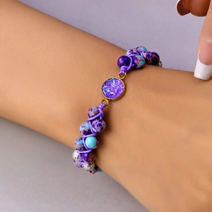Detalle macro de la pulsera hecha a mano de cuentas de piedra natural púrpura y disco dorado