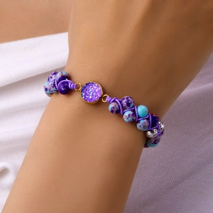 Primer plano de pulsera tejida a mano con piedras naturales púrpuras y amuleto estelar