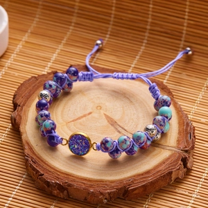 Detalle de pulsera bohemia tejida a mano con piedras naturales púrpuras y colgante dorado