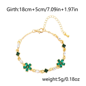 Detail von goldenem Blumenarmband mit grünen Kristallen und Kleeblatt-Anhängern