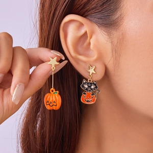 Close-up of asymmetric Halloween earrings with gold stars, pumpkins and black cats