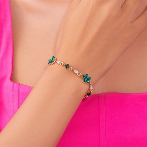 Details eines goldenen Blumenarmbands mit grünen Edelsteinen und weißen Zirkonen