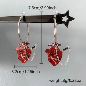Detail showing anatomical heart and knife charm earrings with size specs on a display stand