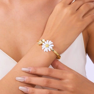 Detailweergave van madeliefje emaille armband en bijenbedel om de pols voor elegante stijl