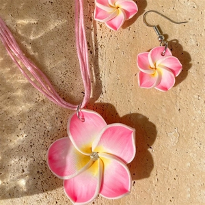 Makroansicht des Schmucksets mit Frangipani-Blüten aus Harz und feinen Strasssteinen