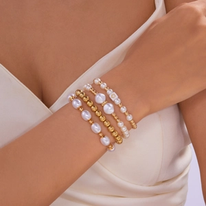 Set van vier gelaagde faux parel en gouden kraal armbanden met hart en bloem motieven