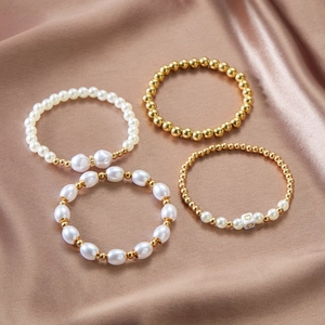 Detail van de vierdelige gelaagde armbandset met imitatieparels en gouden kralen op satijn