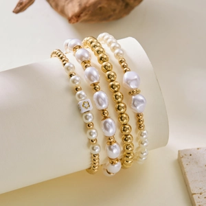 Detail van vierdelige parel- en gouden kralen armbandenset op een stijlvolle standaard