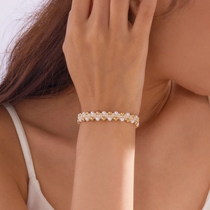 Detail van geweven imitatieparel armbandenset met gouden kralen en wit vezelkoord