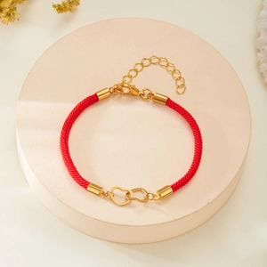 Detail of red braided couple bracelet featuring interlocking gold heart charms