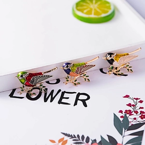 Detailed view of three colorful enamel bird brooches with rhinestones on golden branches