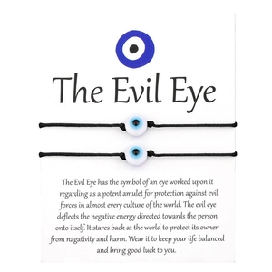 Κοντινό πλάνο από δύο πλεκτά βραχιόλια Evil Eye παρουσιασμένα σε περιγραφική κάρτα δώρου