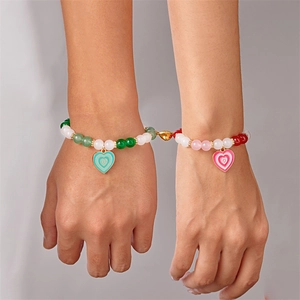 Dettaglio della chiusura magnetica a cuore che unisce due braccialetti con perline colorate