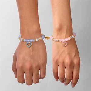 Dettaglio di braccialetti di coppia con perline rosa e blu e chiusura a cuore magnetico