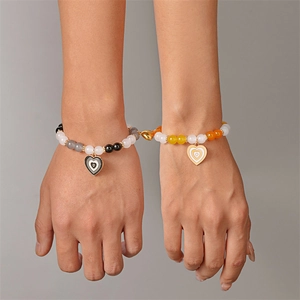 Dettaglio della chiusura magnetica a cuore che unisce due braccialetti di perline colorate