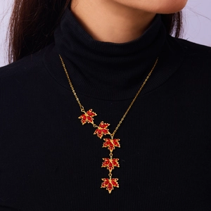 Dettaglio collana a foglia d'acero con strass rossi su maglione nero di alta qualità