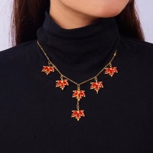 Dettaglio della collana a foglia d'acero con strass rossi su maglia nera a collo alto