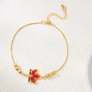 Dettaglio del bracciale con foglia d'acero dorata, zircone rosso e catena regolabile