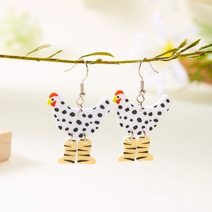 Dettaglio degli orecchini a forma di pollo in acrilico appesi a un ramo di legno