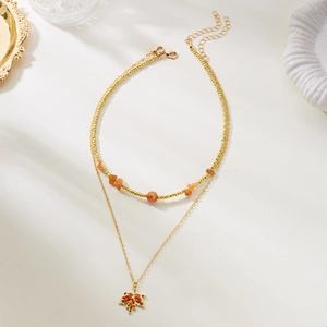 Dettaglio della collana a doppio strato con foglia d'acero, pietre arancio e cristallo