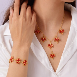 Elegante set di gioielli con foglie d'acero e cristalli rossi su camicia bianca
