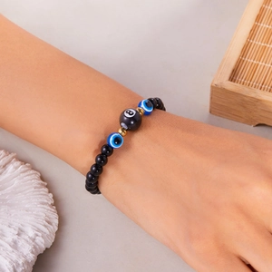 Detail van een 8mm blauwe boze oog kralenarmband met zwarte kralen om een pols