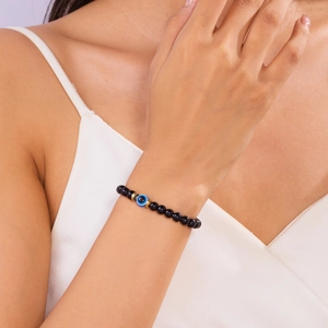 Detail van zwarte kralenarmband met het boze oog en goudkleurige tussenstukjes