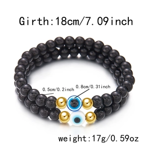 Detailweergave van 8mm zwarte kralenarmbanden met boze oog bedeltjes en gouden afstandhouders