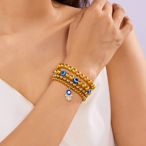 Detail van gouden kralenarmbanden met Hamsa-hand en blauw boze oog om de pols gedragen