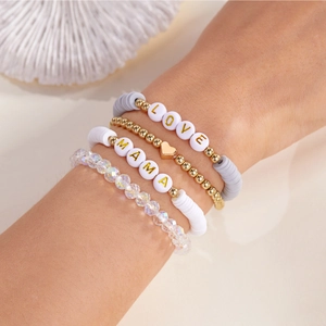 Nahaufnahme von 4er-Set Armbändern mit LOVE und MAMA Perlen am Handgelenk einer Frau