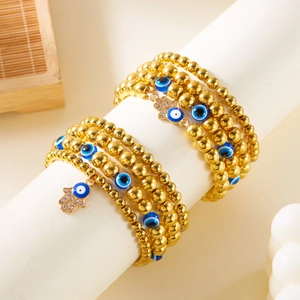 Gouden Evil Eye kralenarmband set met Hamsa Hand hanger op witte standaard