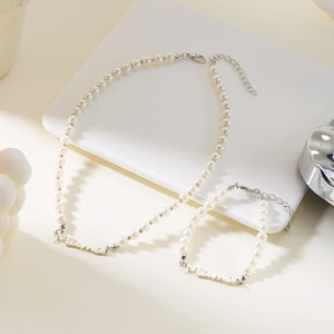Gros plan sur l'ensemble collier et bracelet en perles avec pendentif Mama en argent