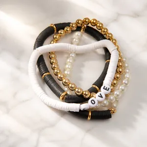 Detail eines mehrlagigen Heishi-Perlen- und Perlenarmband-Sets mit LOVE-Buchstaben