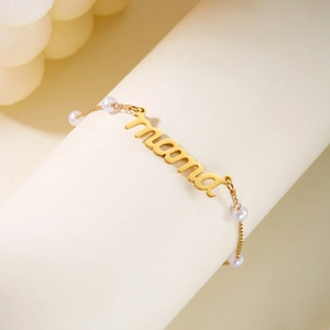 Gros plan du collier doré MAMA avec perles élégantes sur un support de bijoux