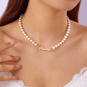 Gros plan d'un collier de perles avec pendentif Mama doré porté par un mannequin