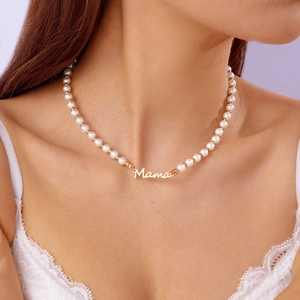 Détail du collier de perles élégant avec pendentif MAMA doré porté au cou