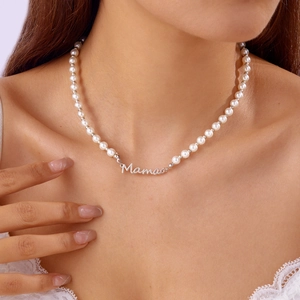 Détail du collier de perles blanches avec pendentif Mama en argent porté par un mannequin