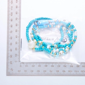 Detalle de pulseras bohemias de cuentas con colgante de concha y ojo turco azul