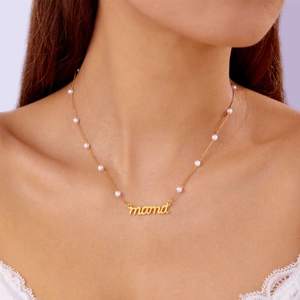 Gros plan d'un collier pendentif MAMA doré avec perles élégantes sur un mannequin
