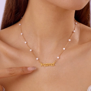 Gros plan d'un collier MAMA doré avec perles blanches porté par un mannequin en mode