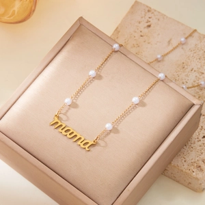 Détail du collier doré MAMA avec perles blanches intégrées dans un écrin à bijoux élégant