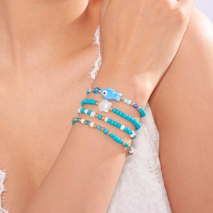 Detalle de pulseras bohemias con cuentas, pez azul, concha marina y amuleto del ojo