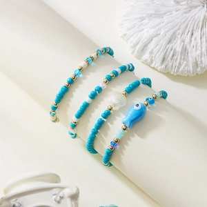 Detalle de set de cuatro pulseras bohemias de cuentas con dijes de concha y pez en azul