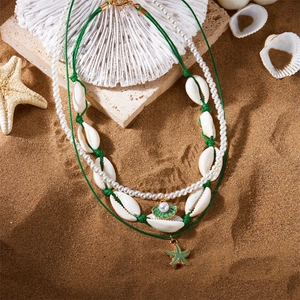 Detail von 3-teiligem Boho-Halsketten-Set mit Seestern, Muscheln und Perlen auf Sand