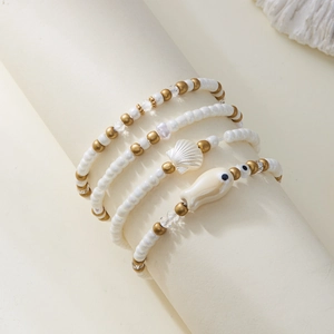 Detalle de un juego de cuatro pulseras de cuentas con conchas blancas y dijes de peces
