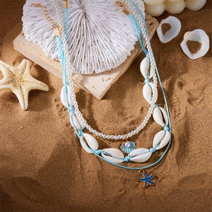 Detaillierte Nahaufnahme einer dreilagigen Boho-Seestern- und Perlenkette am Strand