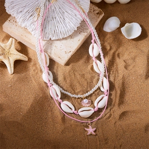 Detailaufnahme der Ozean-Halsketten mit Muscheln und Seesternen auf feinem Sand