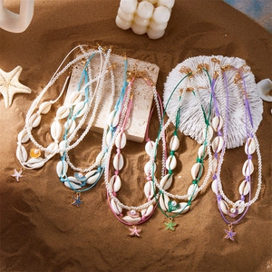 Böhmisches mehrlagiges Halsketten-Set mit Perlen und Muscheln auf sommerlichem Sandstrand