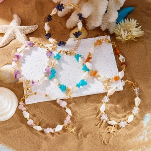Boho-Strandarmbänder mit bunten Steinen, Muscheln und Seestern-Anhängern auf Sand